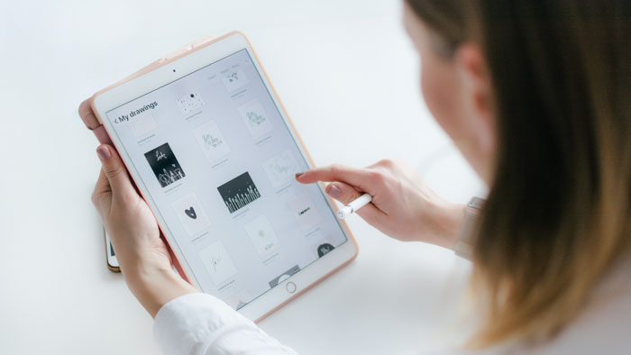 A woman looks at graphs and drawings on her tablet.