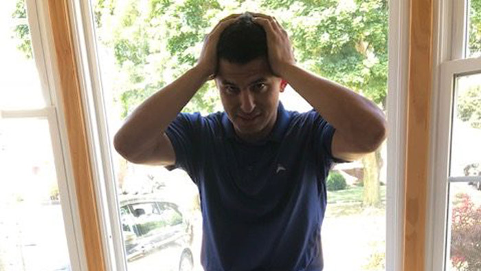 A man shows stress by holding his head in his hands.