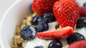 Berries and yogurt top a bowl of granola.
