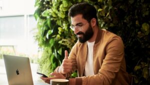 A man gives a thumbs up to a Zoom call on his laptop.