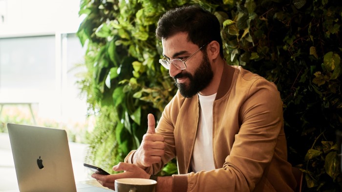 A man gives a thumbs up to a Zoom call on his laptop.