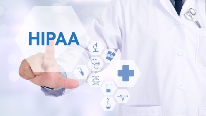 A doctor presses on a holographic button that reads, "HIPAA."