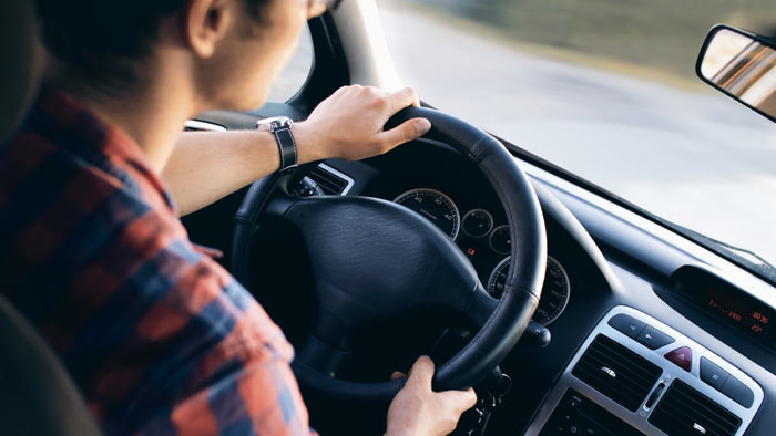 A young adult drives a car.