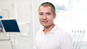 A man smiles at the camera from inside of a doctor's office.