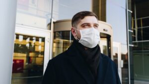 A man walks downtown while wearing a mask.