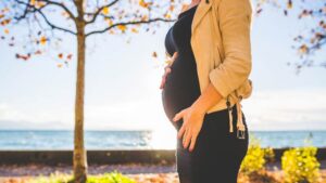 A pregnant woman places a hand on her baby.