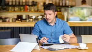 A business owner tries to run calculations while looking at his tablet.