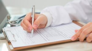 A person fills out a document attached to a clipboard.