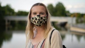A woman smiles while wearing a mask with sunflowers on it.