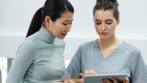 A woman speaks with a doctor, who shows her something on a tablet screen.