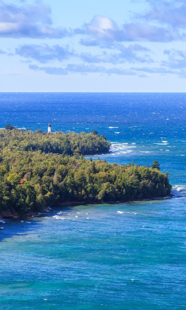 The Au Sable lighthouse stands out against the blue lake water behind it.