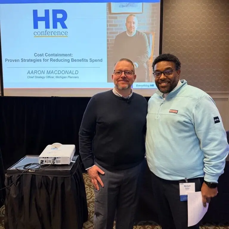 Michigan Planners' Aaron MacDonald poses with a conference attendee at Aaron's panel. His presentation reads, "HR Conference. Cost Containment: Proven strategies for reducing benefits spend."