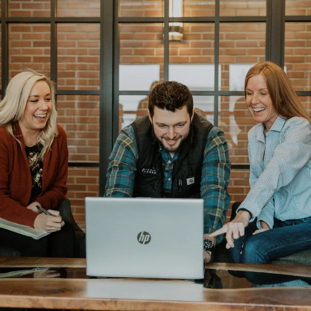 Three Michigan Planners team members collaborate at work. They're all laughing.