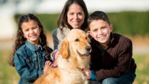A mother, her two children, and their golden retriever pose for a photo.