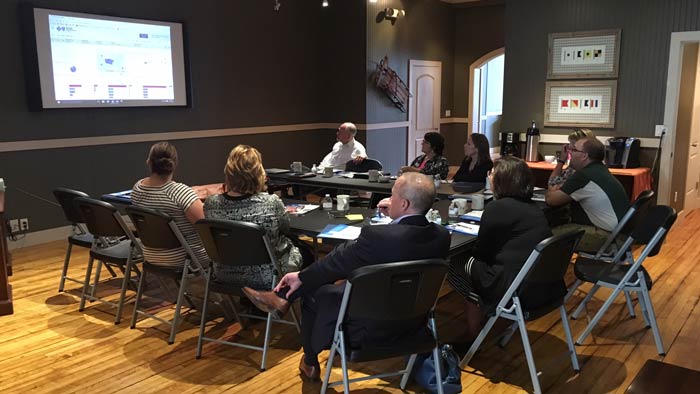 People gather around a table to discuss a presentation at the Insurance Brokers In Michigan E3 Seminar