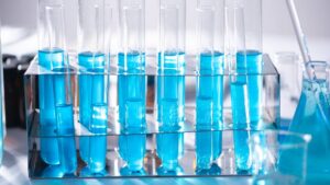 Test tubes filled with blue liquid rest on a desk.
