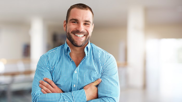 A professional man smiles in his office.