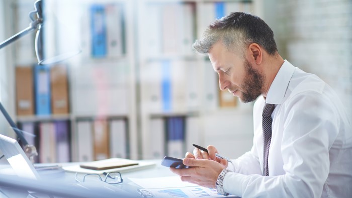 A man scrolls through messages on his phone.