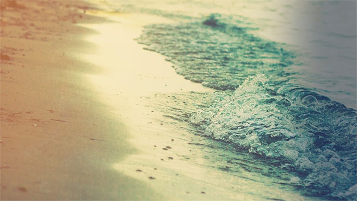 Waves roll in on a sandy beach.