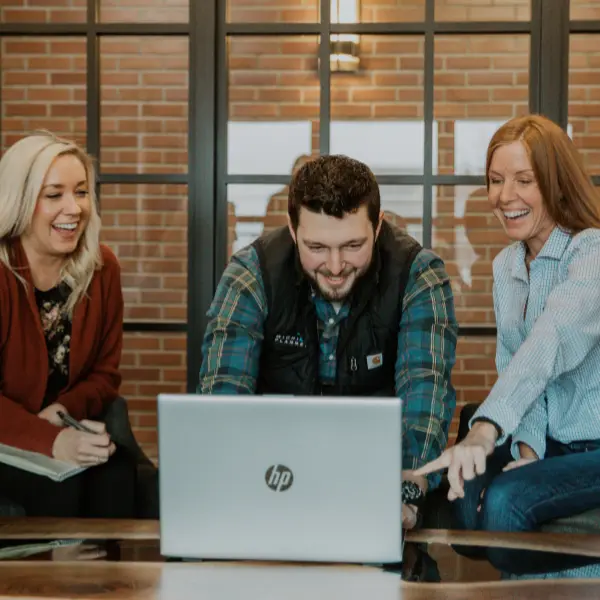 Three Michigan Planners team members collaborate at work. They're all laughing.