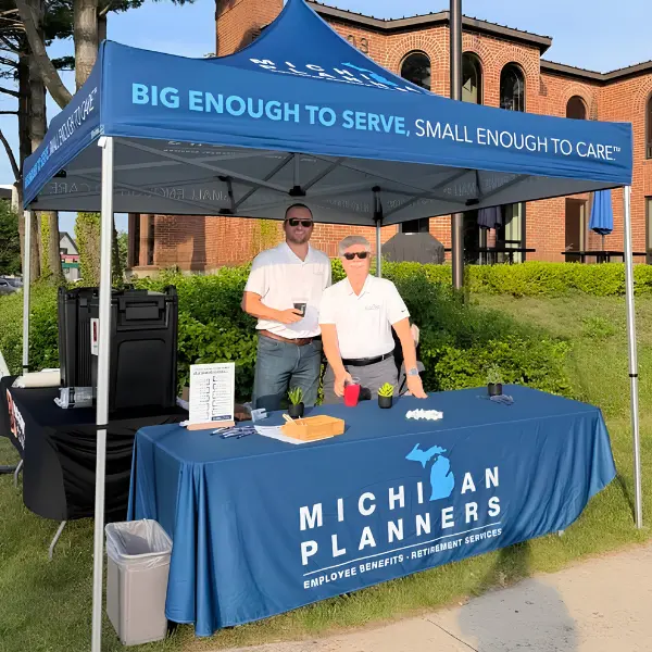 Two members of the Michigan Planners Medicare team smile from inside a Michigan Planners tent.