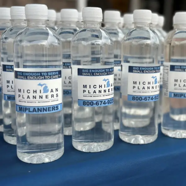 Several water bottles line a table. Each one has a label showing the Michigan Planners logo and 800-674-9235.